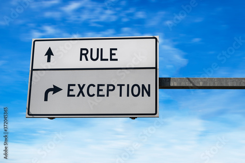Rule versus exception. White two street signs with arrow on metal pole. Directional road. Crossroads Road Sign, Two Arrow. Blue sky background.