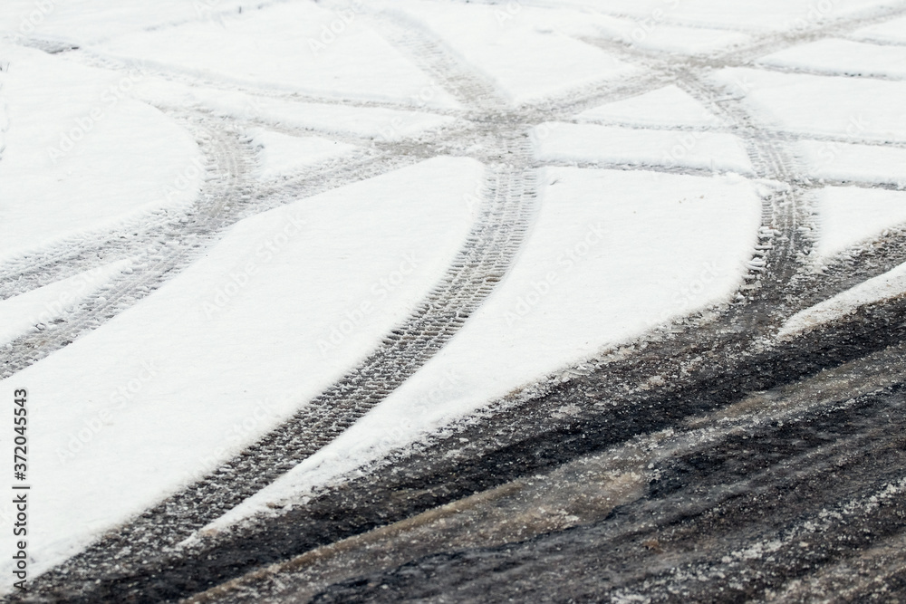 Traces of car tires in the snow on the turn during the thaw. Caution: slippery road
