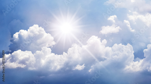 Panorama of blue sky with white curly clouds and bright sun
