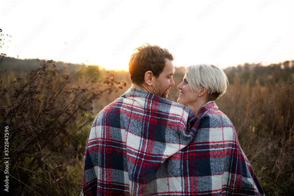Rear view of young couple in love on a walk in autumn nature.