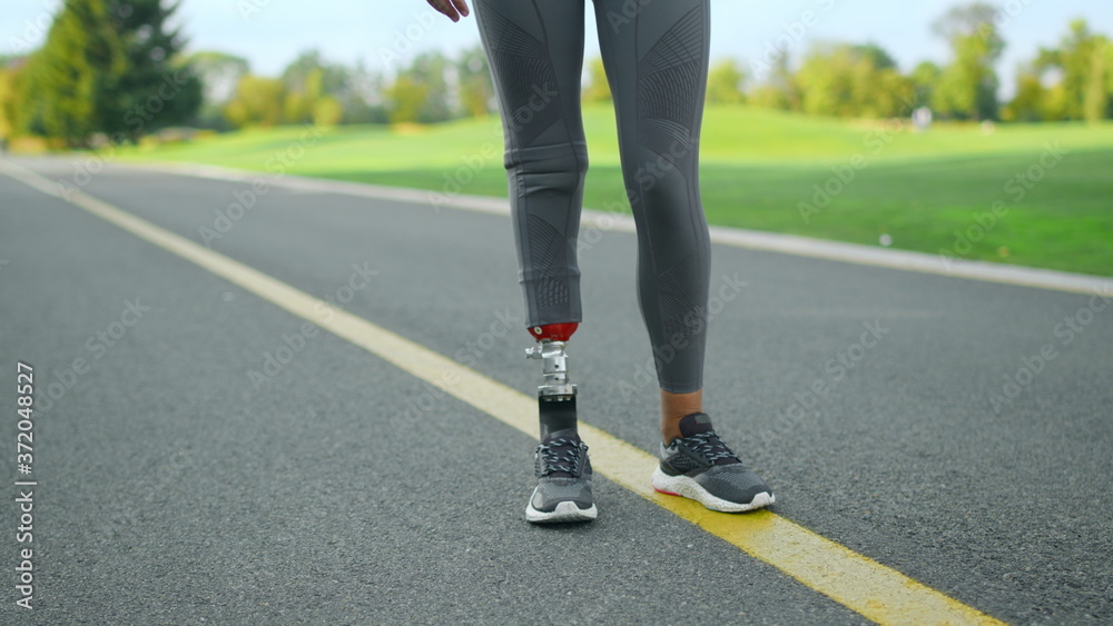 Disabled athlete warming legs before workout in park. Woman training outdoors Disabled athlete warming legs before workout in park. Woman training outdoors