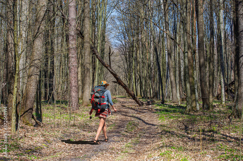 A girl with a backpack in a stylish hat walks through the spring forest. Ukraine © tns2710