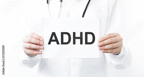 Doctor holding a card with text ADHD, medical concept.