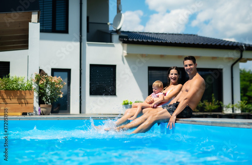 Young family with small daughter in swimming pool outdoors in backyard garden. © Halfpoint