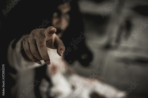 Woman in ghost or zombie on halloween festival at dark place, pointing her hand to front. Horror or halloween festival concept.