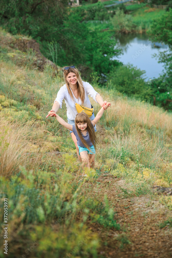 Mom and daughter walk by the hand along the path on the rocky slope Mom and daughter walk by the hand along the path on the rocky slope
