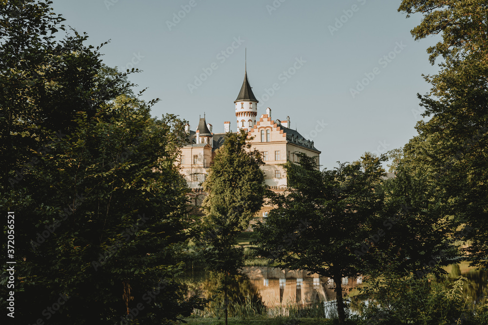 Fototapeta premium The view of the Radun castle in empire style, known landmark in Radun in Czech republic, above the castle pond during the sunny summer day with clear sky in background