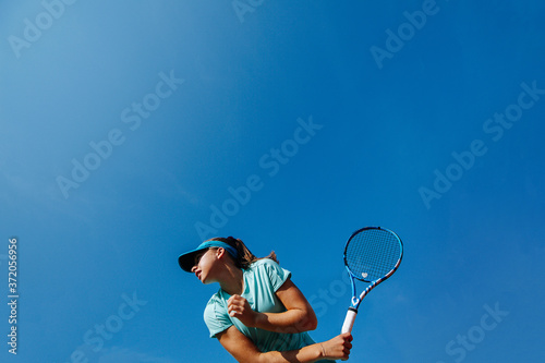 Obraz na plátně Low angle photo of girl playing tennis, holding racket backhand