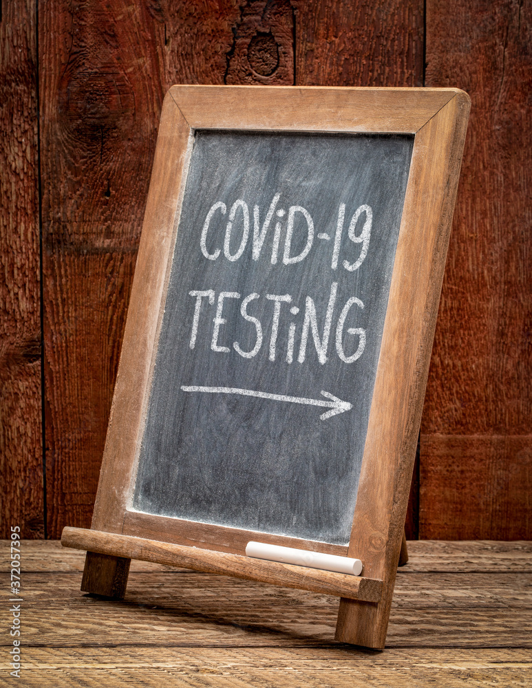 covid-19 testing - white chalk handwriting on a blackboard, coronavirus pandemic concept