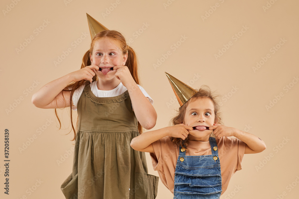 Waist up portrait of two girls making funny faces and grimacing while ...