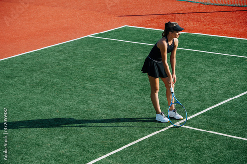 Resting girl playing tennis on a new court, leaning on a racket