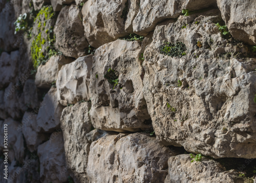 An ancient wall made of rough stones, perspective view.