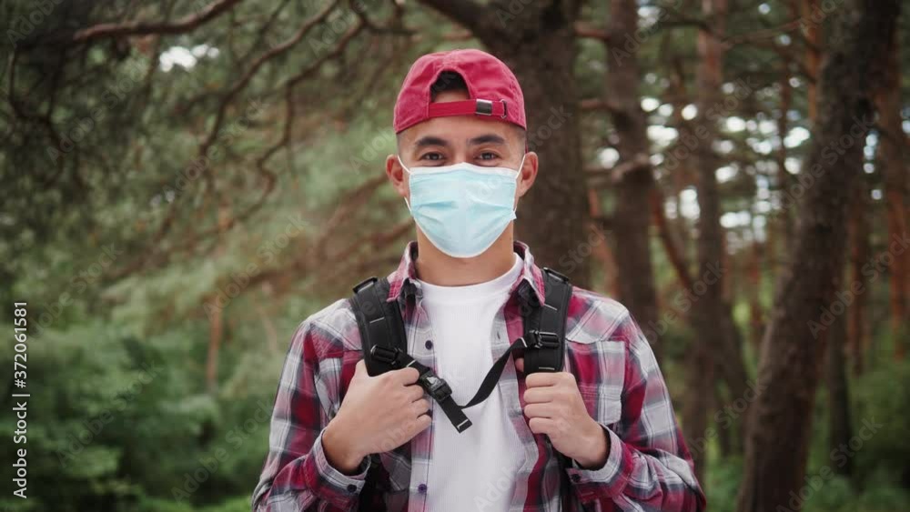 Young asian korean tourist man in forest, wearing medical protective mask, safe travel, hiking in park, coronavirus pandemic, covid 19 safety in public space. Student hiker backpacker on nature Young asian korean tourist man in forest, wearing medical protective mask, safe travel, hiking in park, coronavirus pandemic, covid 19 safety in public space. Student hiker backpacker on nature