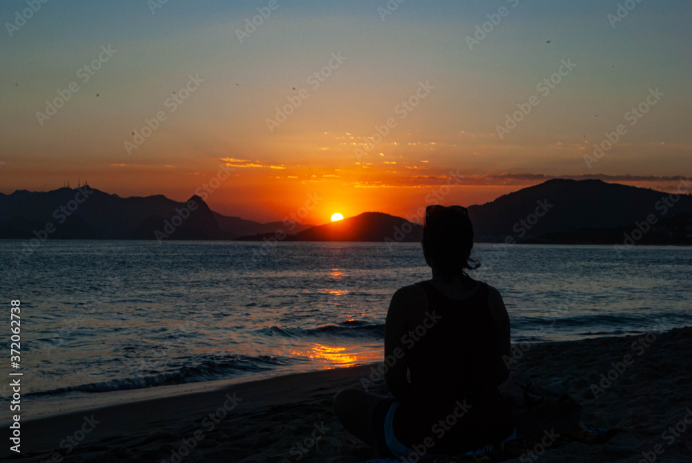 Silhouette of a woman on the beach at sunset.
