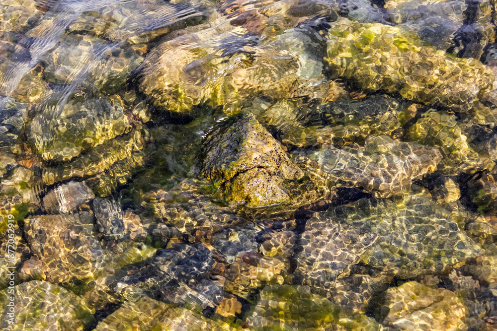 The texture of the water of a lake with clear water, at the bottom of which there are stones.