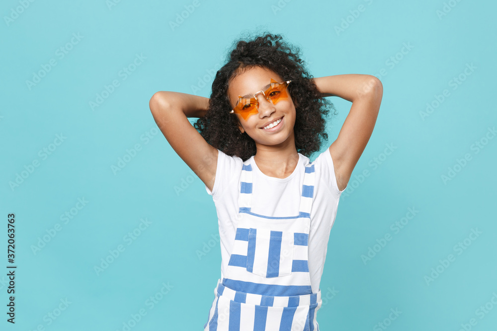 Charming little african american kid girl 12-13 years old in striped clothes star glasses isolated on pastel blue background studio. Childhood lifestyle concept. Mock up copy space. Put hands on head. Charming little african american kid girl 12-13 years old in striped clothes star glasses isolated on pastel blue background studio. Childhood lifestyle concept. Mock up copy space. Put hands on head.