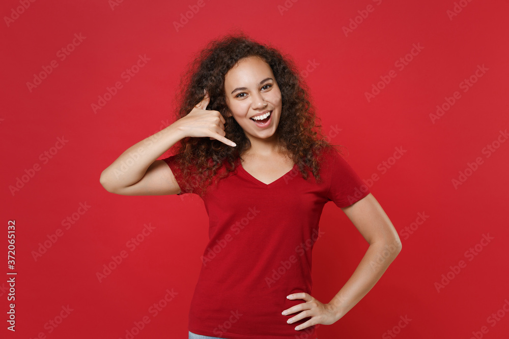 Funny young african american woman girl in casual t-shirt posing isolated on red background studio portrait. People lifestyle concept. Mock up copy space. Doing phone gesture like says call me back. Funny young african american woman girl in casual t-shirt posing isolated on red background studio portrait. People lifestyle concept. Mock up copy space. Doing phone gesture like says call me back.