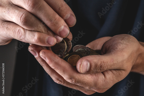Men's hands hold ruble coins close-up on a dark background. Concept of poverty and misery