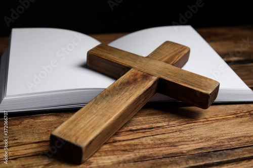 Christian cross and Bible on wooden background, closeup. Religion concept