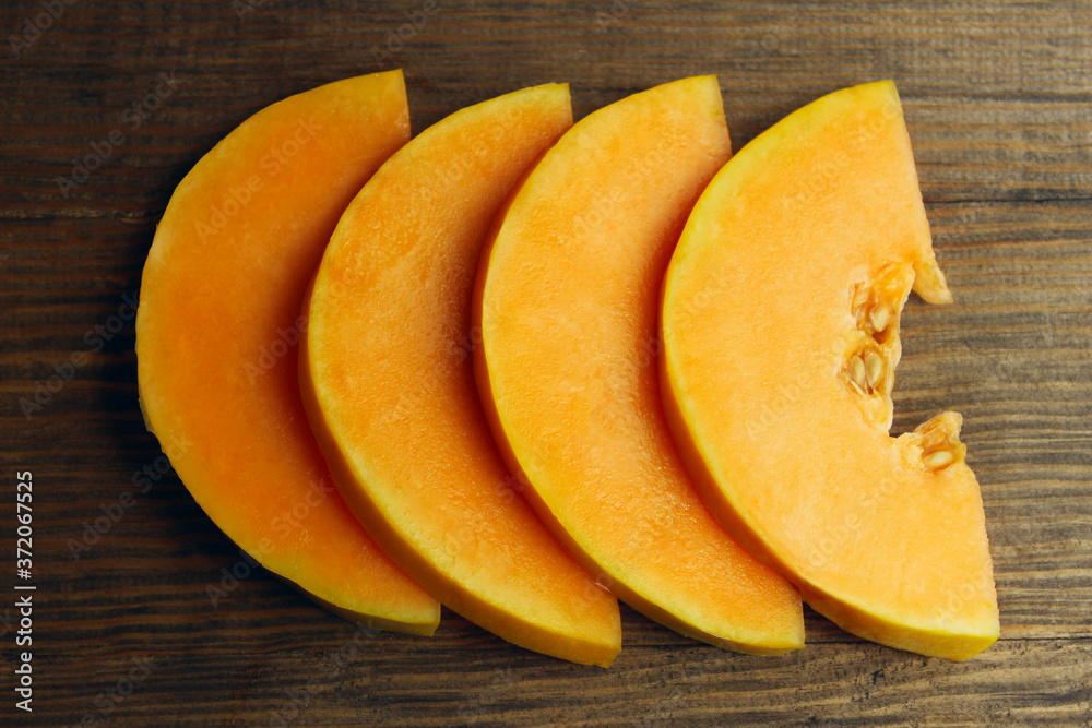 Yellow melon sliced on brown wooden background. Food background. Melon on the table. Yellow melon sliced on brown wooden background. Food background. Melon on the table.