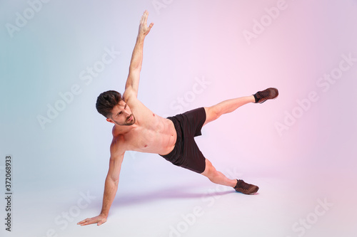 Full length portrait of young fitness sporty strong guy bare-chested muscular sportsman isolated on white background. Workout sport motivation lifestyle concept. Standing in side plank on one hand.