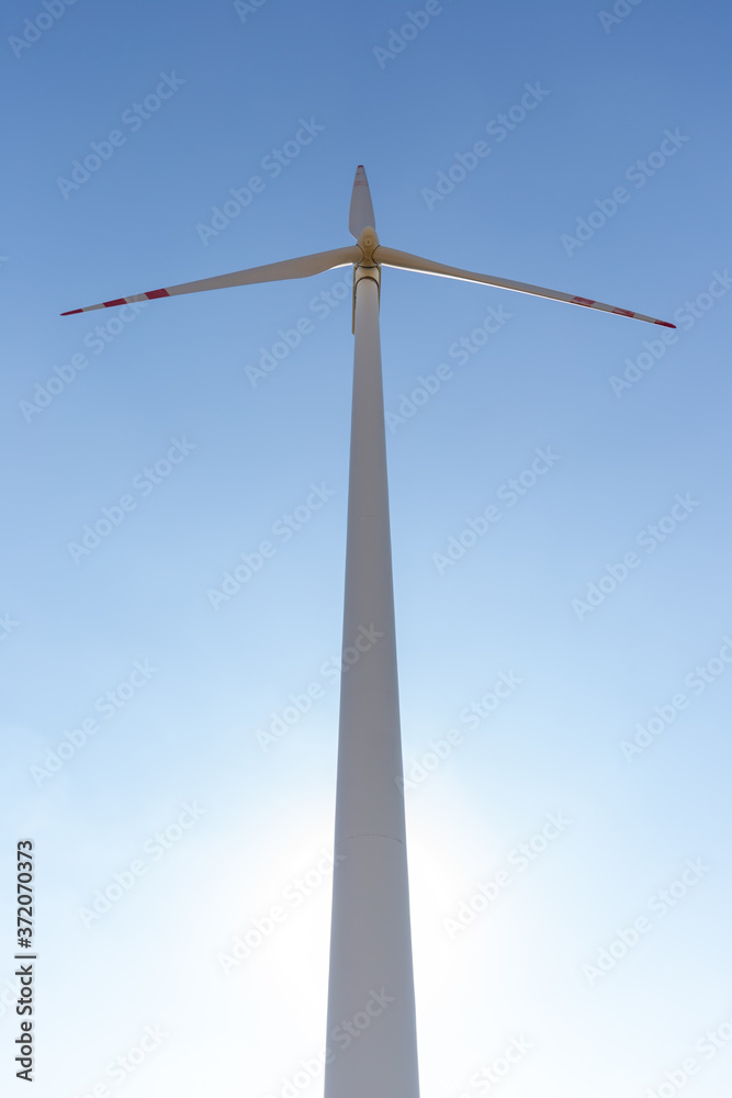 Wind turbine under blue sky in summer, renewable energy concept photo Wind turbine under blue sky in summer, renewable energy concept photo