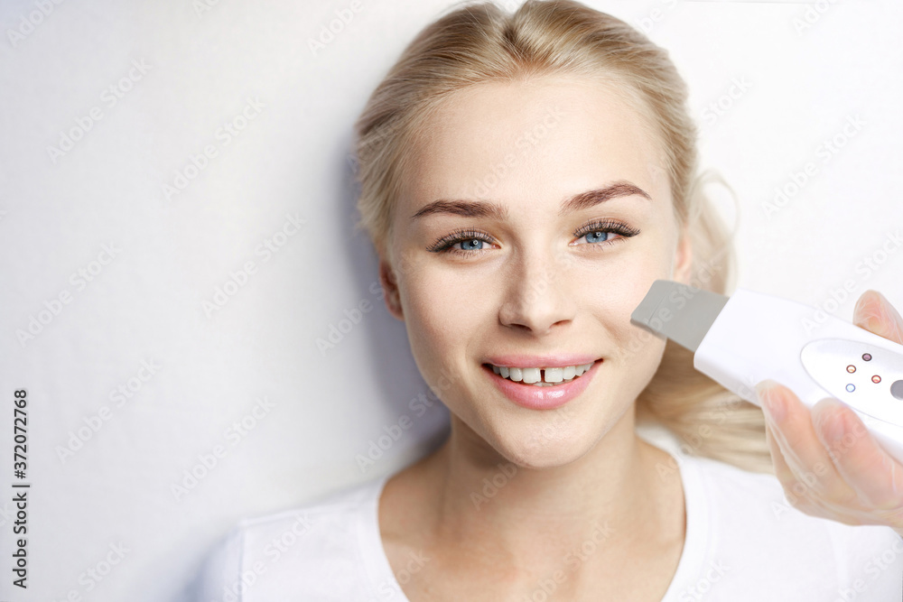 Beautiful young woman in beauty salon. Woman getting facial treatment. Female with healthy glow smooth skin. Ultrasonic skin cleansing procedure. Beautiful young woman in beauty salon. Woman getting facial treatment. Female with healthy glow smooth skin. Ultrasonic skin cleansing procedure.