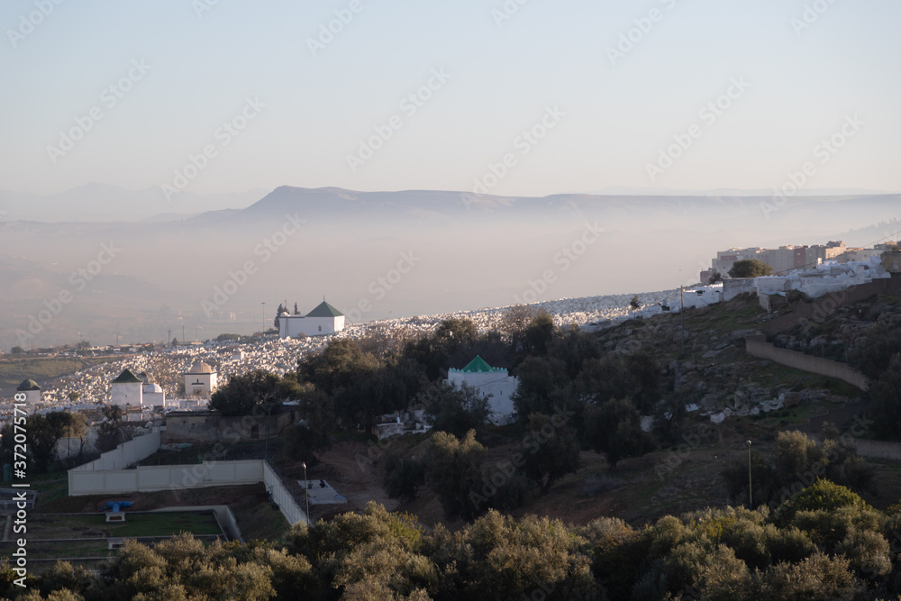 Bab Mahrouk Cemetery Fes Morocco with atmospheric mist and mountains behind
