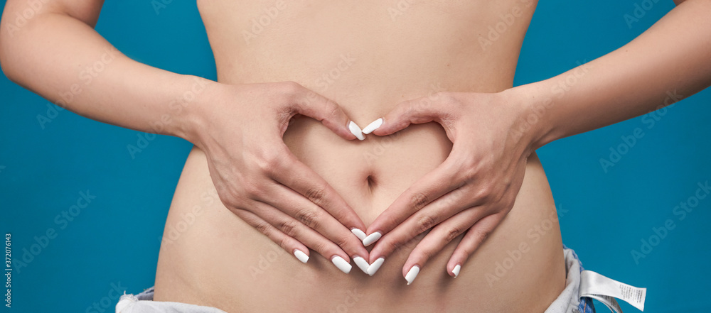  Girl's hands in the form of a heart on her stomach                              
