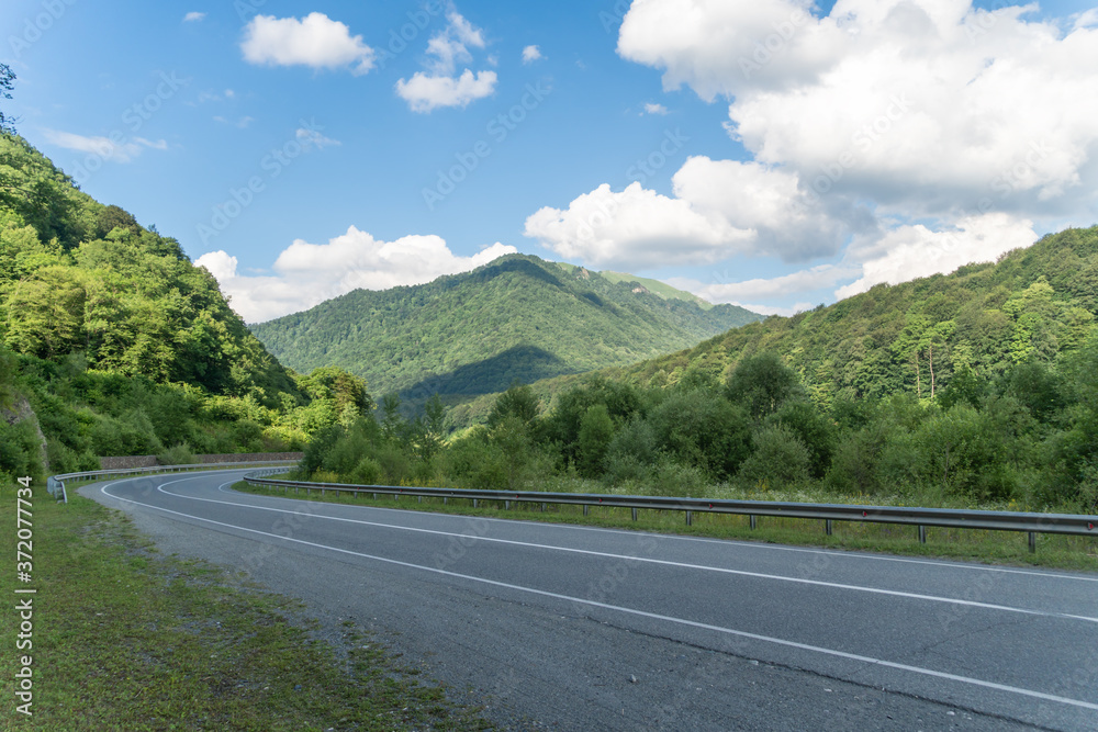 Asphalt road in the mountains with soft sky on the background. Travel concept