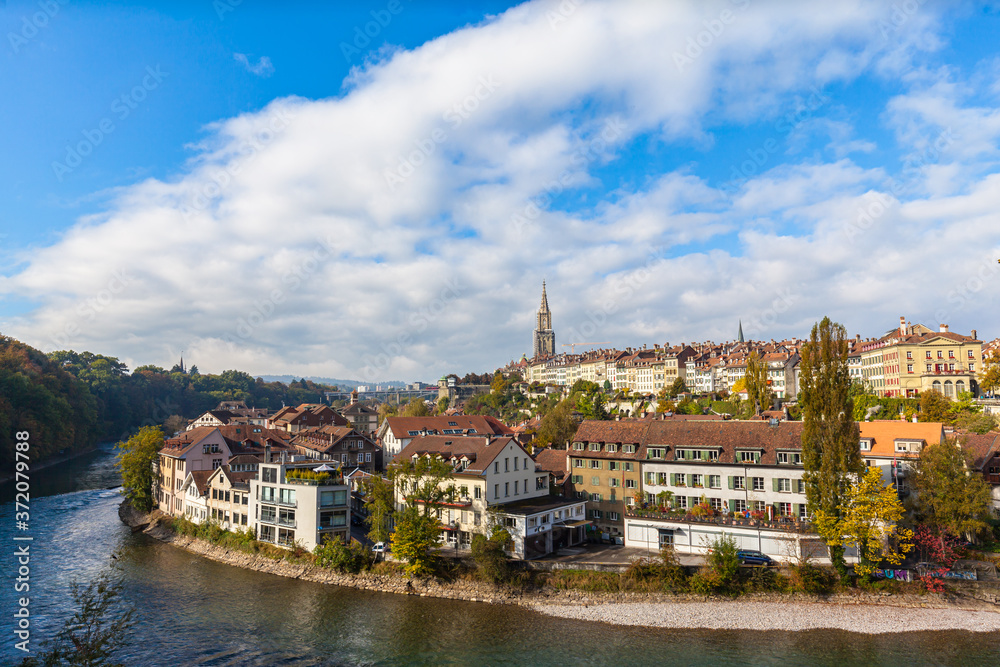 Stunning panorama view of Bern old town with Bern Minster (Münster)cathedral and Aare river flowing around, on sunny autumn day with blue sky and cloud, Switzerland