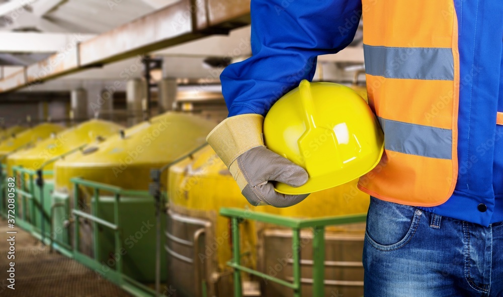 Worker man with helmet in hands on a factory background Worker man with helmet in hands on a factory background