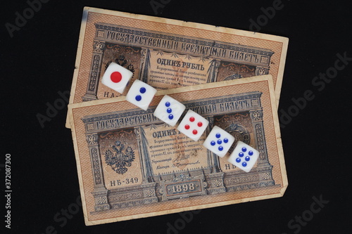 Fotografie Dice against the background of pre-revolutionary ruble banknotes symbolize the u