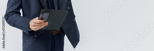 Portrait of a businessman in a blue suit holding an electronic tablet on a white background. No face visible.