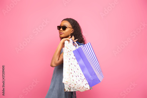 stylish young african lady wearing sunglasses and carrying shopping bags