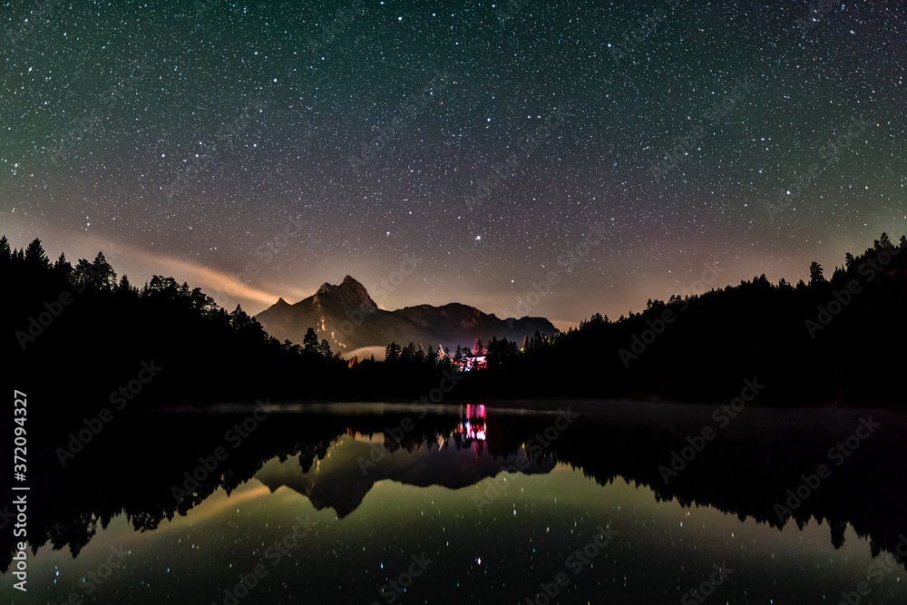 Night sky reflection in lake Urisee with alps mountains in background