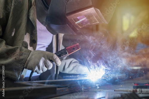 welder welds metal with a welding machine. metal works in the workshop close up. © Петр Смагин