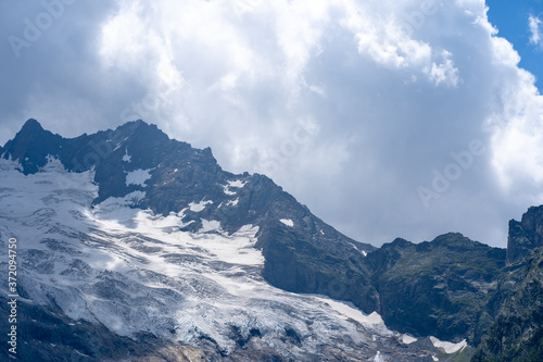 Beautiful mountain landscape in summertime. Mighty mountains with snow in cloudy weather.