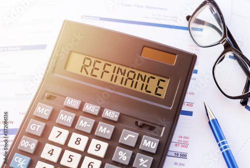 Refinance text on the display of a close-up of a calculator with a glasses and pen photo