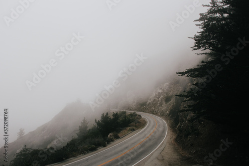 curved road by the ocean covered in fog