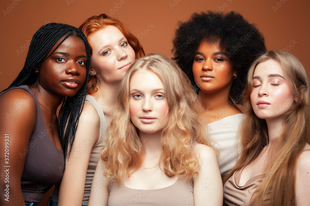 young pretty caucasian, afro, scandinavian woman posing cheerful together on brown background, lifestyle diverse nationality people concept