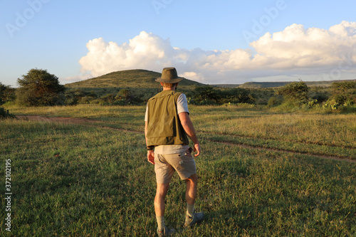 Man walking through grassland at sunset in Kenya, Africa