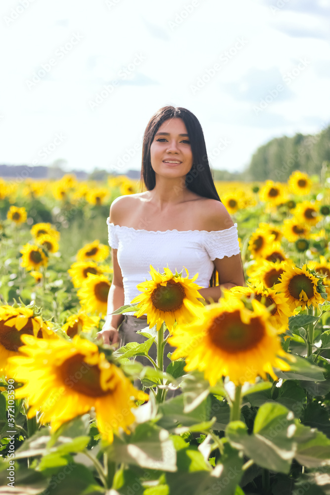 Beautiful brunette woman in a white top on the field with sunflowers. Yellow sunflowers. Close plan. Beautiful brunette woman in a white top on the field with sunflowers. Yellow sunflowers. Close plan.