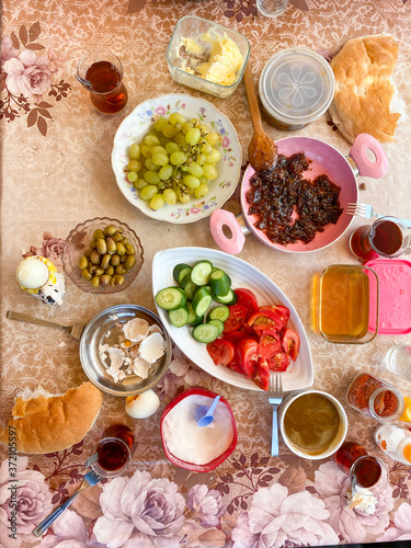 Delicious Turkish Traditional Breakfast serving on table ingredients with Egg, Butter, Olives, Fresh Vegetables, Various Cheese, Bread Pisi, Patty and Black Tea.