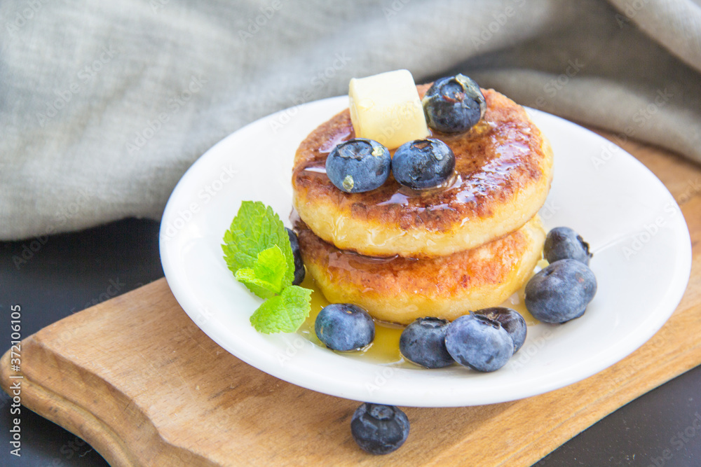 A healthy breakfast of pancakes, berries, butter, and honey