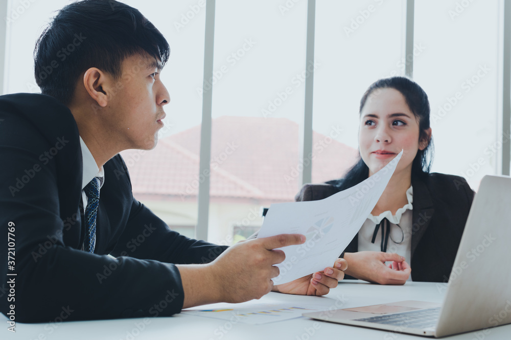 Asian male and female colleagues are discussing work with graph paper and a notebook. Asian male and female colleagues are discussing work with graph paper and a notebook.