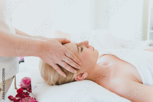 Beautiful woman lying on the bed for a spa asia massage at luxury spa and relaxation. The masseuse is massaging her face in the spa room.