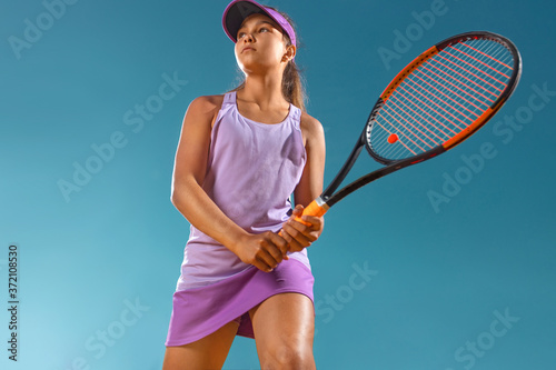 Teenager tennis player. Beautiful girl athlete with racket in pink sporswear and hat on tennis court. Fashion and sport concept. © Mike Orlov