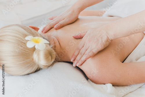Beautiful woman lying on the bed for a spa asia massage at luxury spa and relaxation. The masseuse is massaging her arms and shoulders into the spa room.
