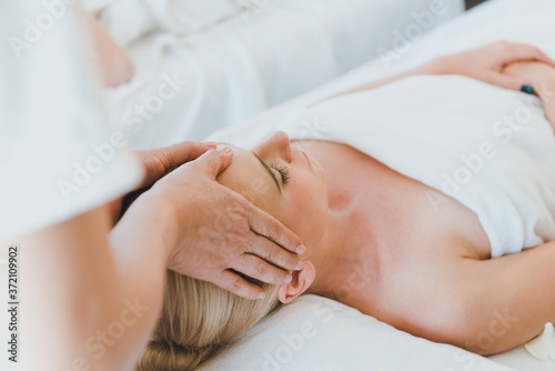 Beautiful woman lying on the bed for a spa asia massage at luxury spa and relaxation. The masseuse massaged her face and head in the spa room.